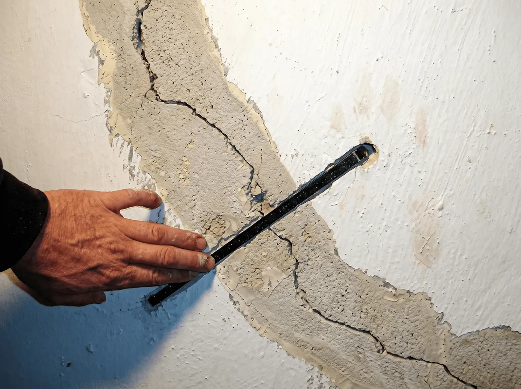 A wall with a large crack is being inspected by a professional in Boca Raton, FL